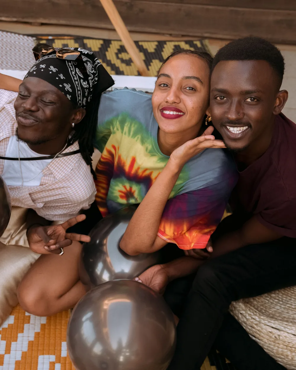 Three friends smiling together at a party with balloons
