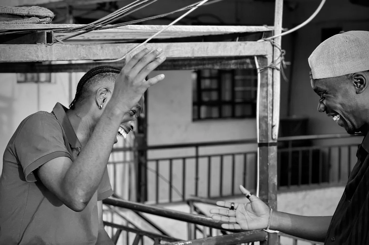 Two friends laughing as they reach out to shake hands