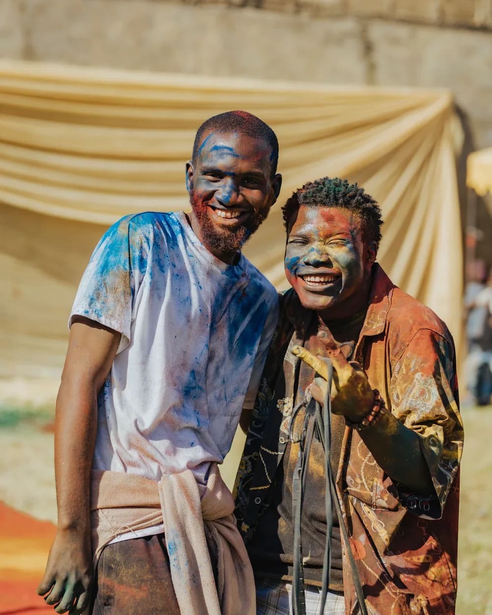 Two friends laughing, their faces dusted with festival colour powder