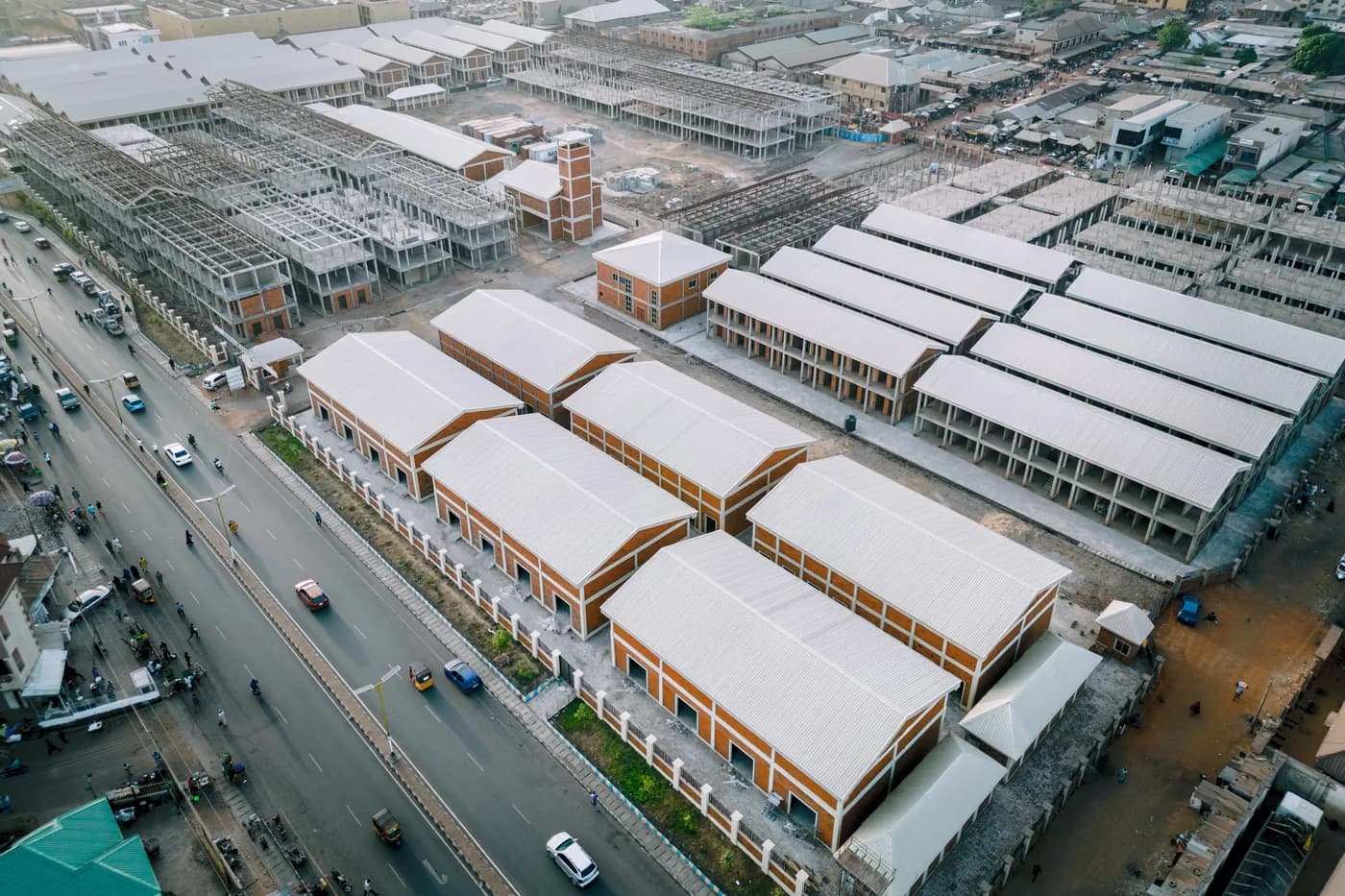 Aerial view of a market with rows of stalls beside a busy road